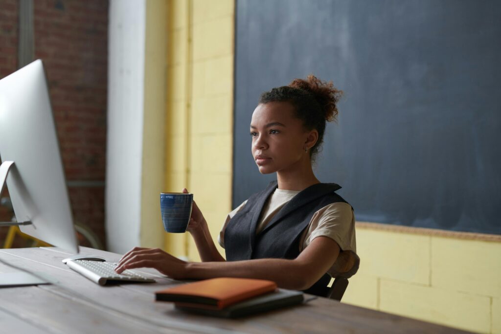 Person working at desk with computer and coffee, symbolizing ADHD morning and evening routines.
